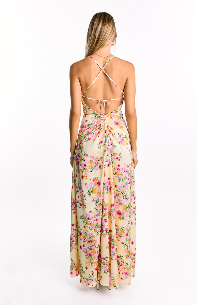 Rear view of a yellow floral satin maxi dress with criss-cross back straps and a ruched tie-back detail