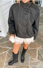 Front view of a black PU jacket showing the funnel neck, button-front, and flap pockets
