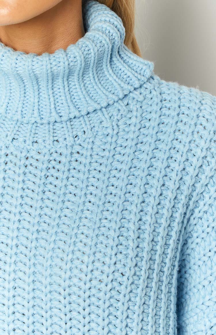 Close-up of the light blue chunky knit sweater dress, showing the ribbed turtleneck and vertical textured stitch