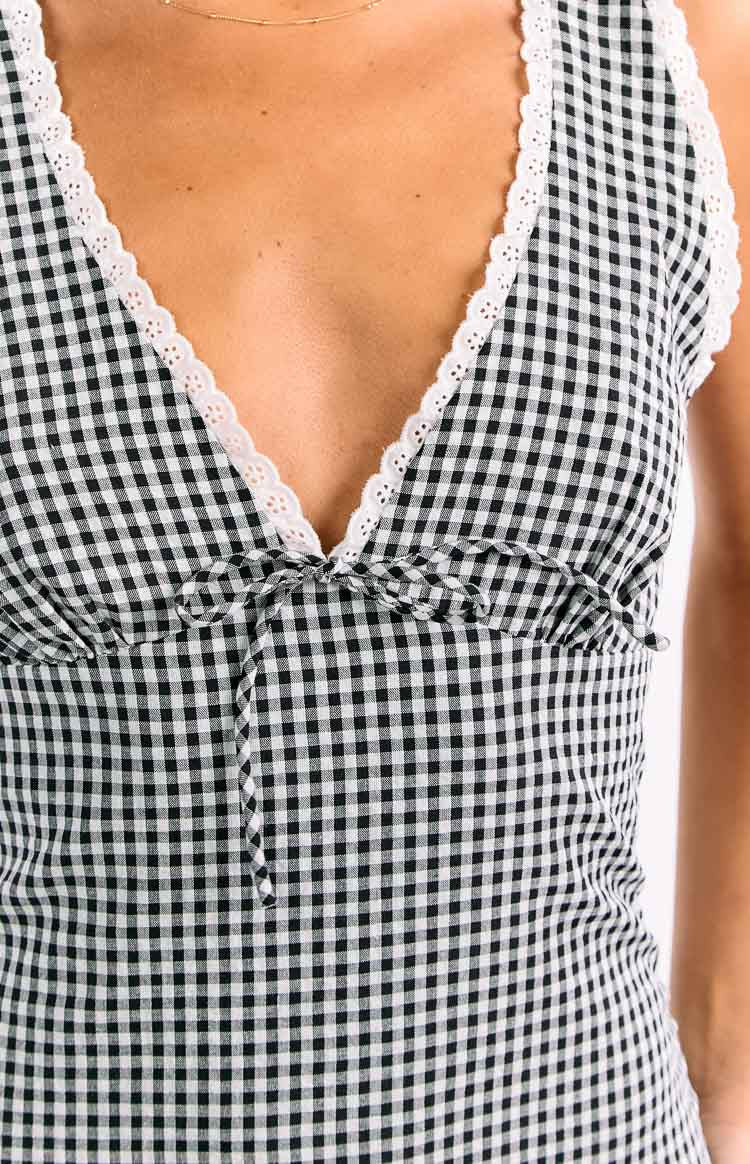 Close-up of the black and white gingham mini dress showing the V-neckline with white lace trim and tie-front detail