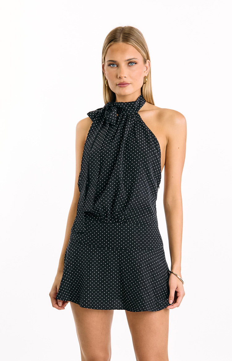 Black polka dot mini dress with a prominent halter neck tie forming a bow at the front