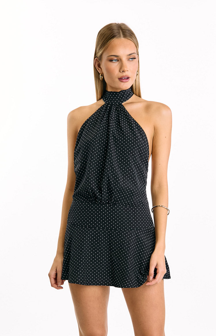 Black mini dress with white polka dots, a gathered halter neckline, and a flowy A-line skirt
