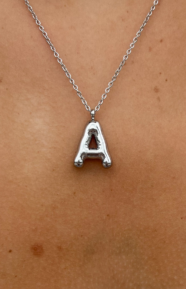 A close-up image focuses a silver chain necklace. The necklace features a chunky bubble-style pendant in the shape of the letter 'A'. The pendant has a smooth reflective melted appearance and hangs from a simple link chain.