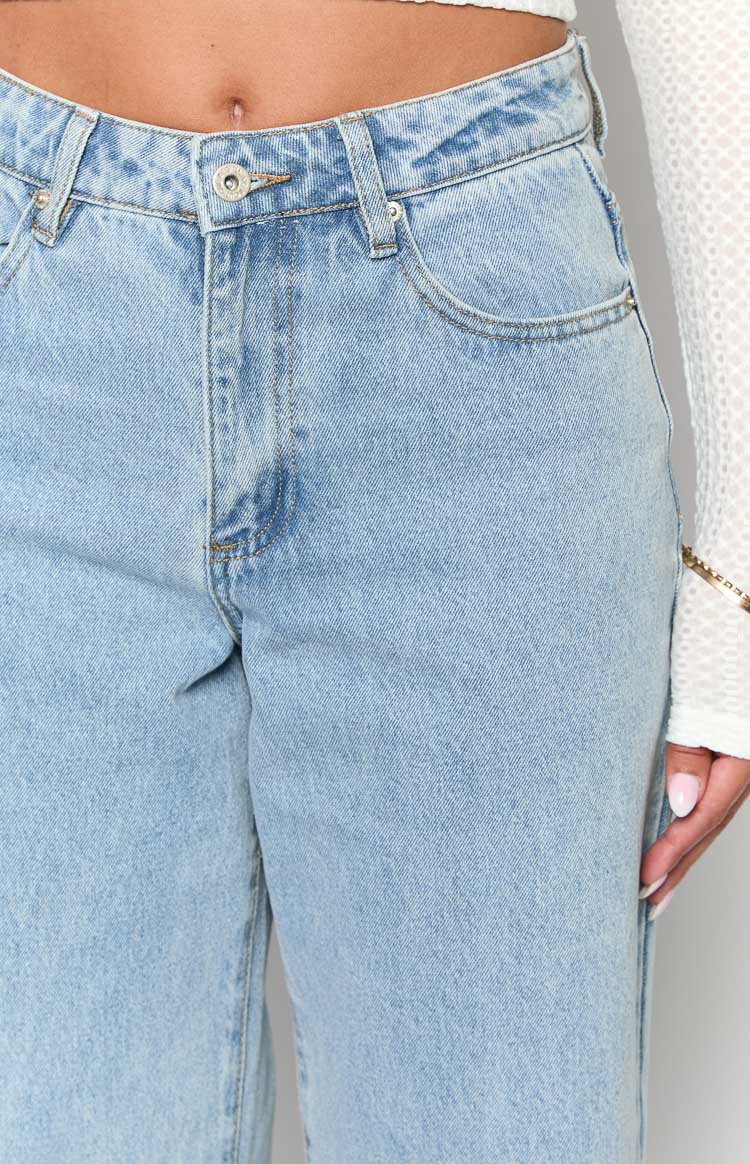 Close-up of the light wash denim mid-rise jeans showing the button closure and front pockets