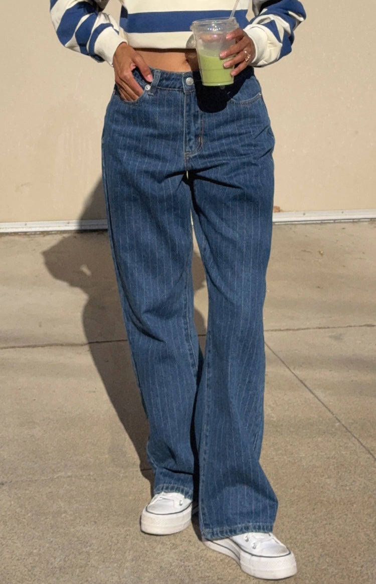 Full length view of mid-wash blue pinstripe slouchy jeans with a relaxed fit and front pocket detail