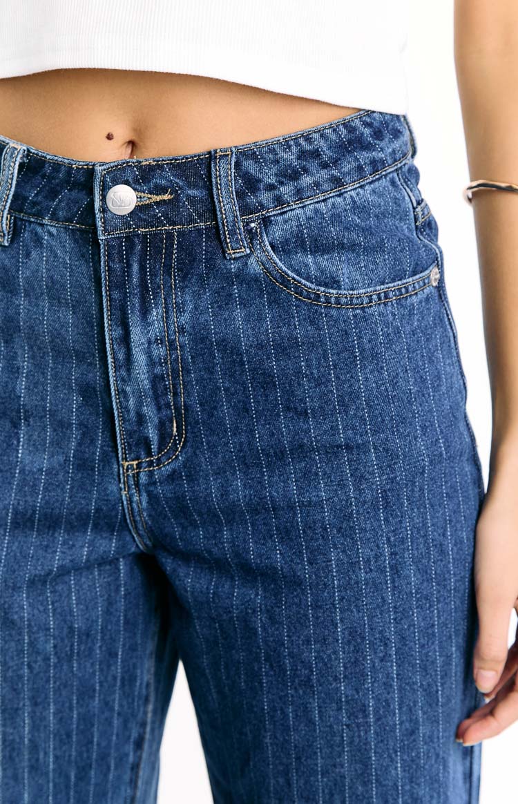 Close-up of the mid-wash pinstripe jeans showing the front button closure, belt loops, and coin pocket