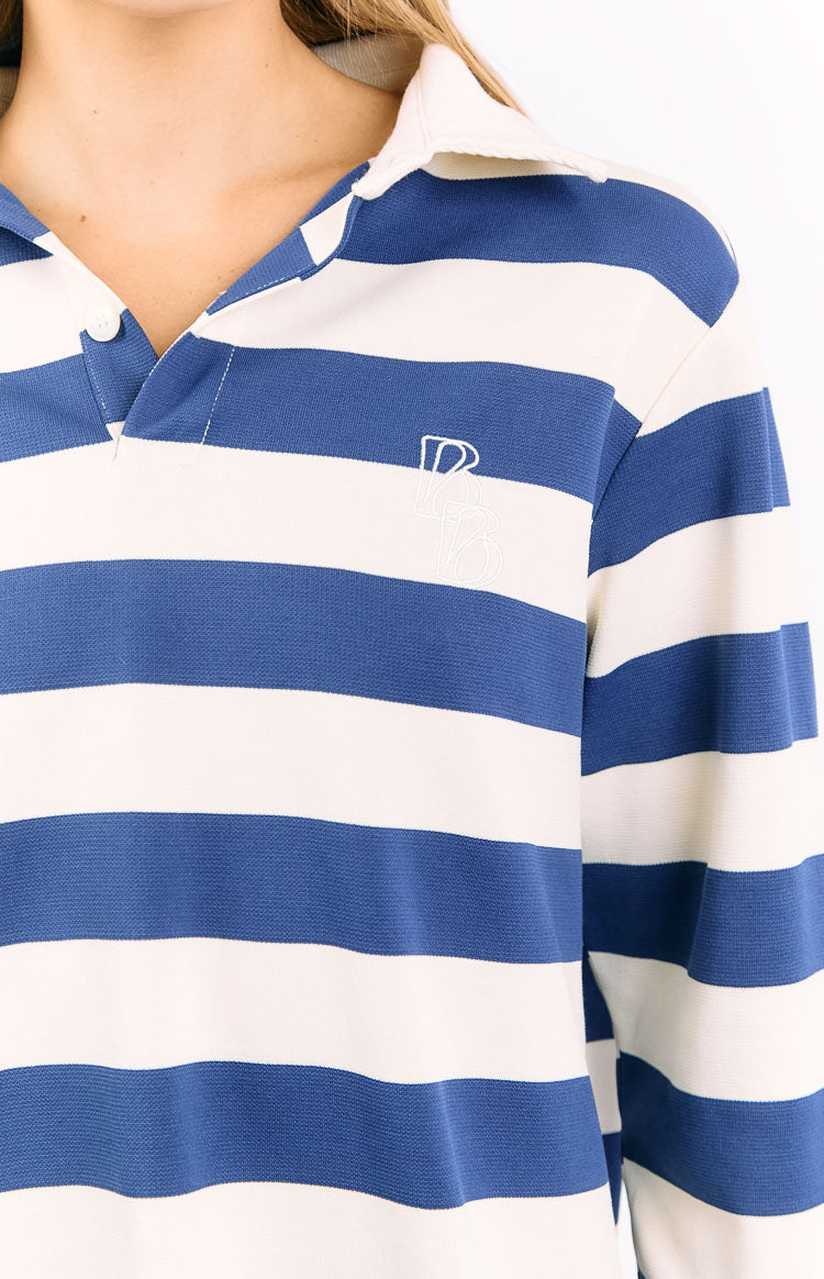Close-up of the white embroidered logo and button placket on a blue and white striped jersey