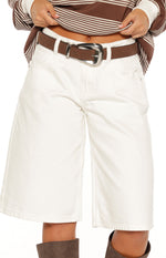 Close-up of the dark brown suedette belt with a curved silver buckle and single prong