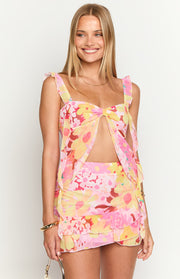 Front view of a pink, yellow, and red floral print chiffon mini skirt with a tiered ruffled hem