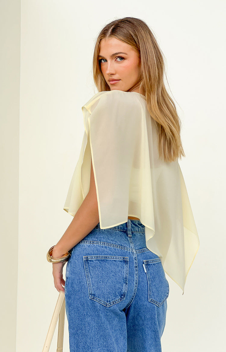 Rear view of a yellow sheer chiffon cape with open arm slits and a flowy, cropped silhouette