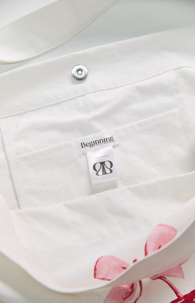 Close-up of the white canvas tote bag's interior showing the magnetic snap closure, internal pocket, and brand label