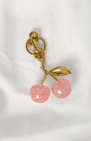 Faux suede brown shoulder bag with a pink glitter cherry keyring with gold details and hardware