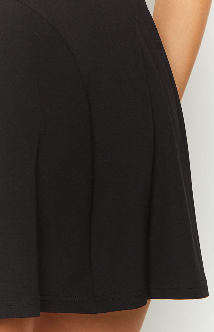 Close-up of the black mini dress's full skirt with soft pleats and a neat hem