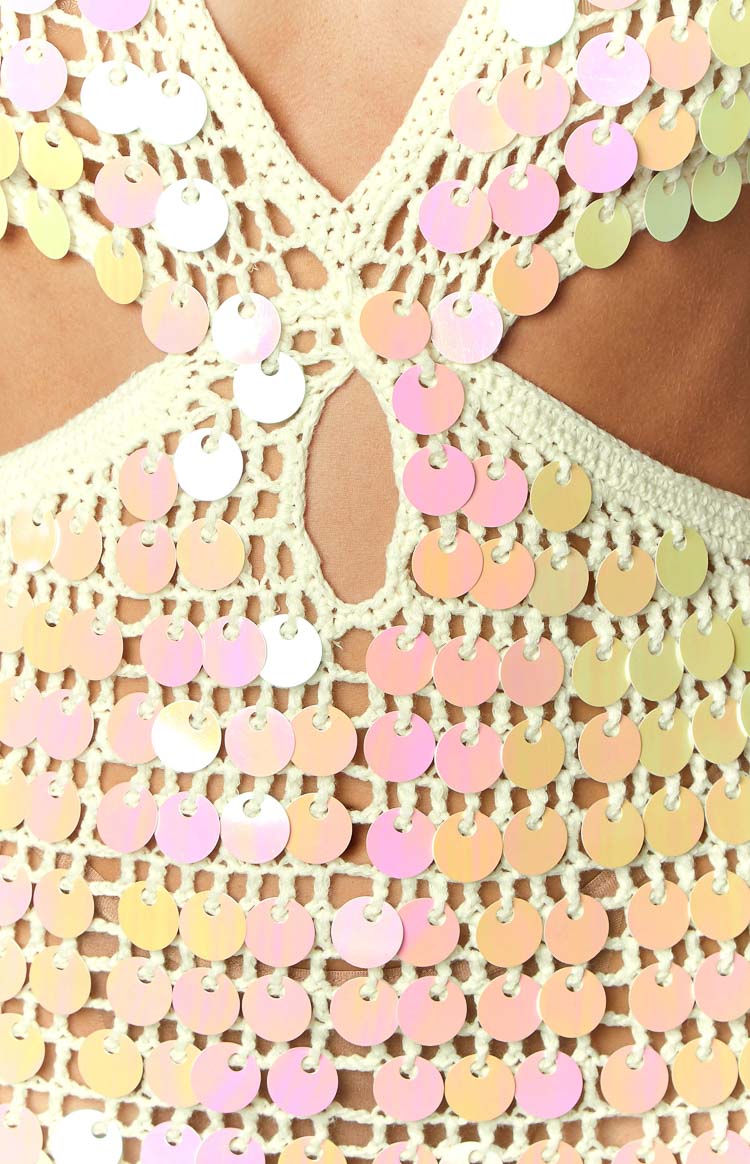 Close-up of the cream crochet knit fabric with iridescent sequins and a central keyhole cutout