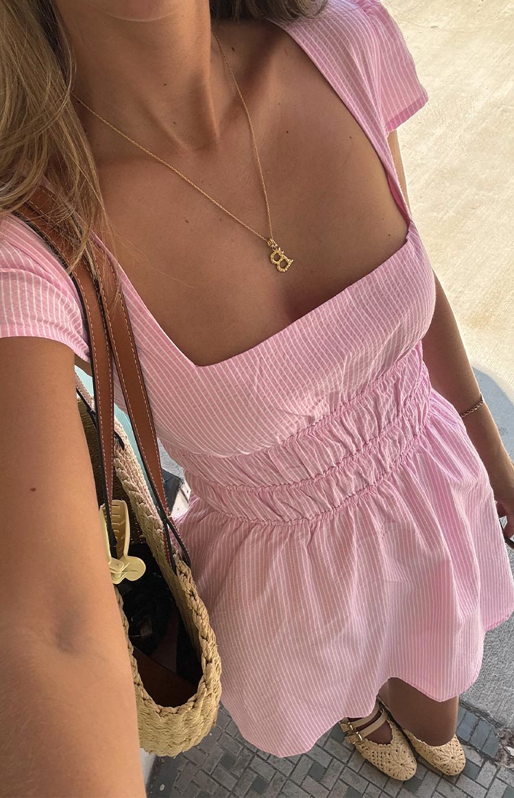 Close-up of a light pink and white striped mini dress with a square neckline and ruched bodice.