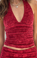 Close-up of a red velvet halter V-neck crop top with an embossed floral pattern and horizontal shirring