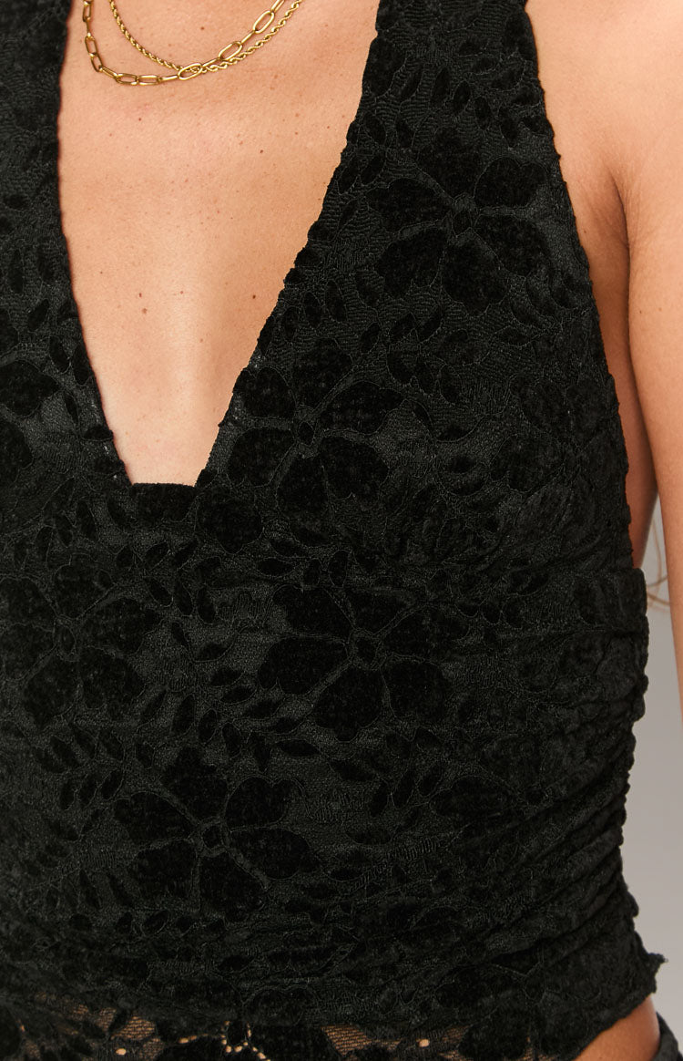 Close-up of the black velvet floral lace texture, deep V-neckline, and side ruching detail