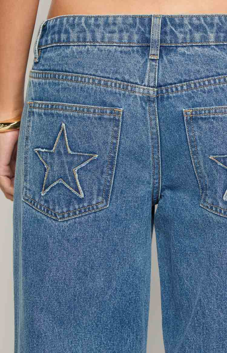 Close-up of the back pockets of mid wash denim jeans with embroidered star outlines