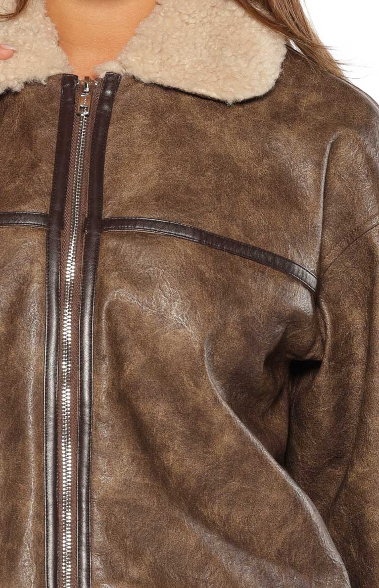 Close-up of the distressed brown faux leather aviator jacket with cream shearling collar and dark brown piping