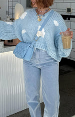 Close-up of the chunky knit texture and white cloud appliques on a cloud blue cropped sweater