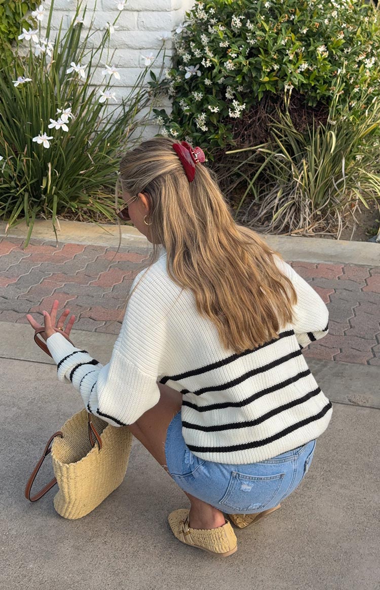 Rear view of a cream knit jumper with thick black horizontal stripes across the back and sleeves