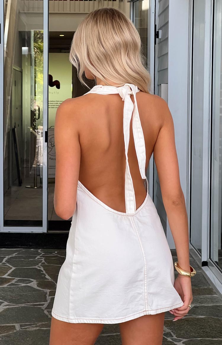 Rear view of a white denim mini dress with a halter neck tie, low open back, and contrast stitching
