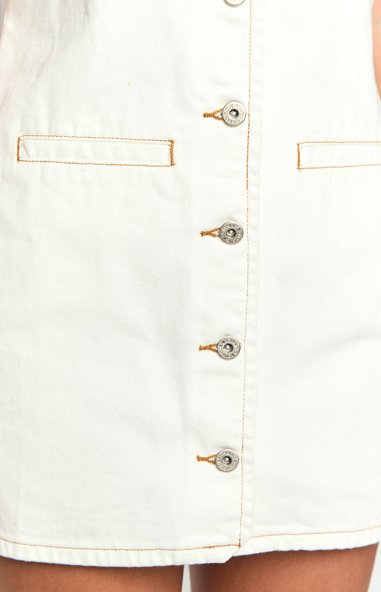 Close-up of white denim mini dress with silver button-front closure, tan contrast stitching, and chest pockets