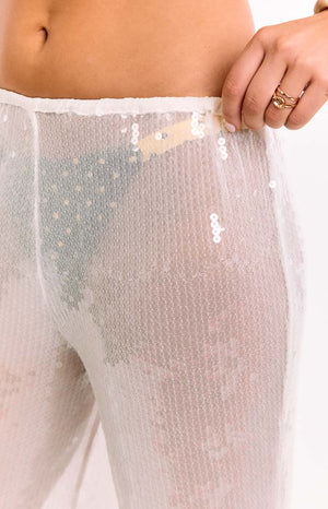 A close-up of our model's waist and hips showing a pair of sheer white sequin pants with a wide-leg cut. You can see through the pants to any bikini bottom.