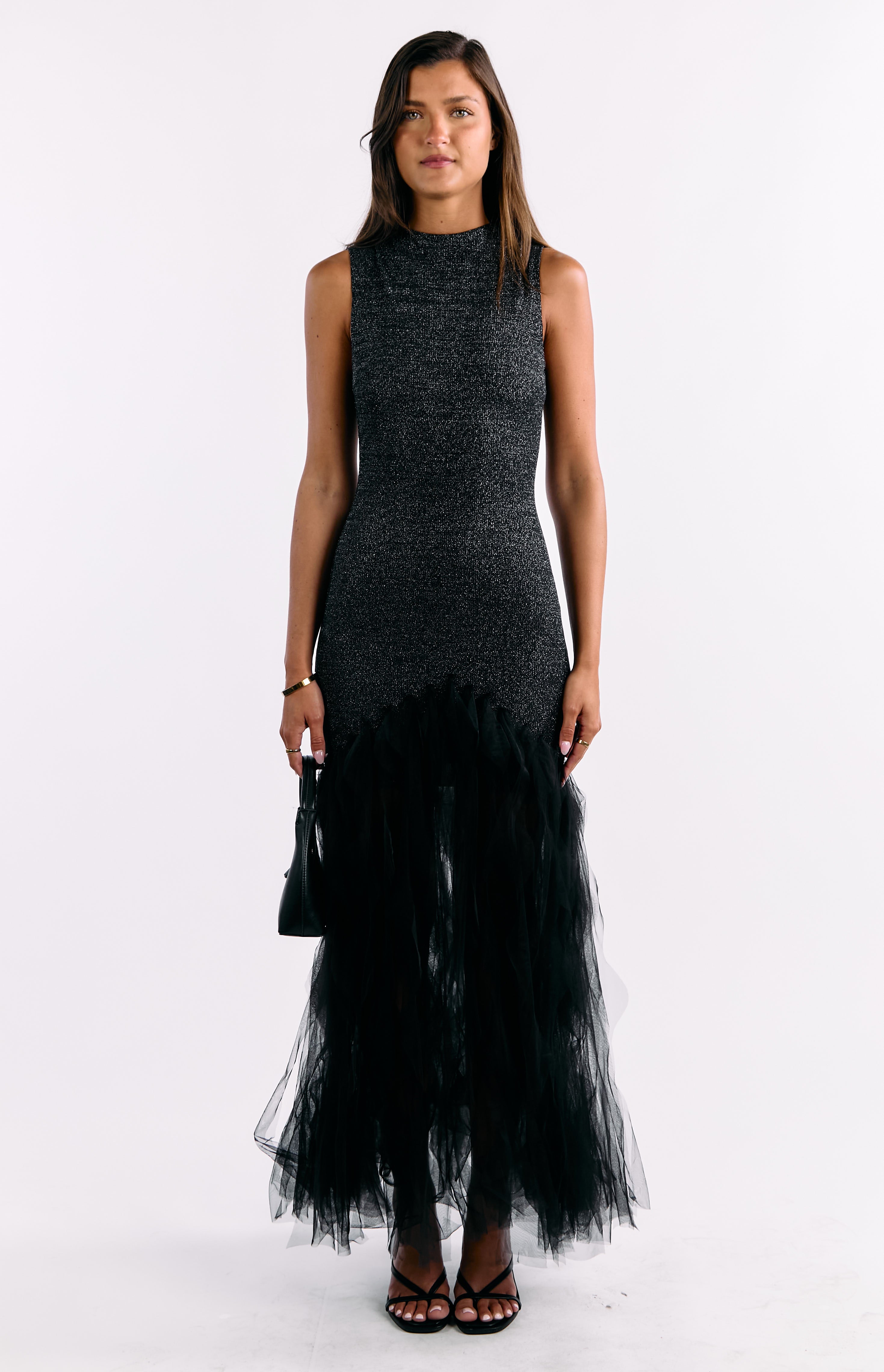 Full length front view of a black sequin sleeveless maxi dress with a high neck and voluminous ruffled tulle skirt