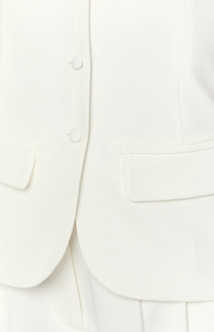 Close-up of the white button-up top with two front buttons and a single flap pocket