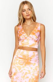 Front view of an orange and pink floral print crop top with a deep V-neckline, gathered bust, and side zipper