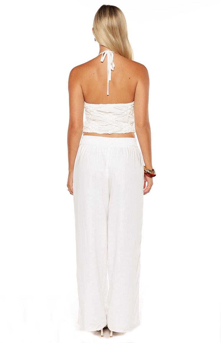 Rear view of a white textured halter top with a tie-neck closure and a ruched back panel