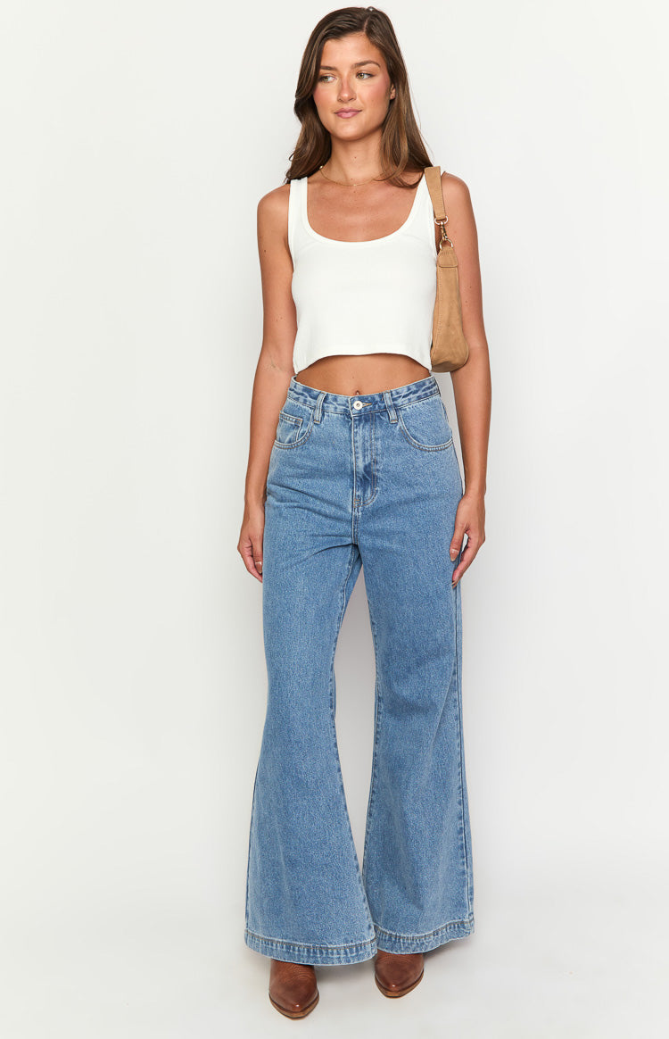 Front view of mid wash blue denim flare jeans with a high waist and wide leg opening