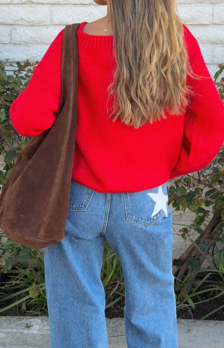 Rear view of mid wash denim flare jeans with a white star detail on the back right pocket