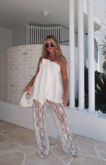 Full length view of white sequin lace sheer wide-leg pants with intricate pattern