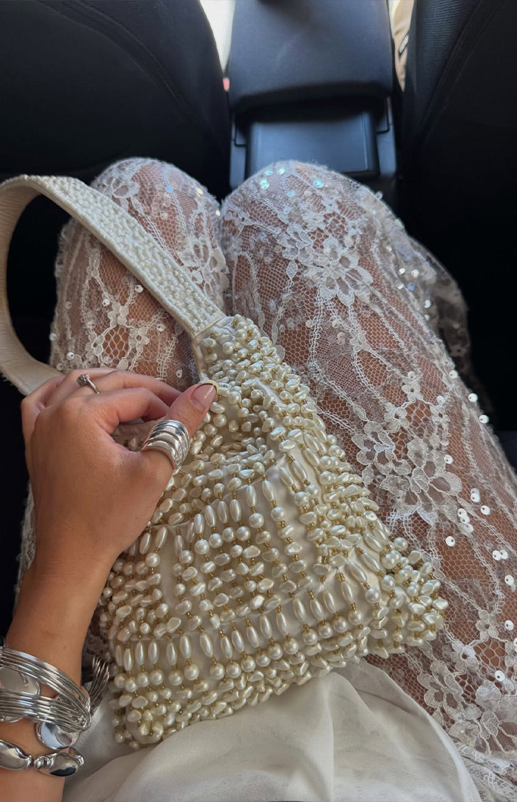 Close-up showing the intricate floral lace pattern and scattered sequins on the sheer white pants