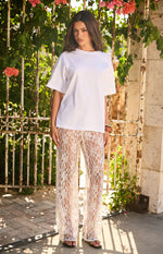 Full length view of white sequin lace sheer pants with a wide-leg fit and intricate floral pattern