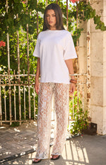 Full length view of white sheer wide-leg pants with all-over floral lace and subtle sequin embellishments