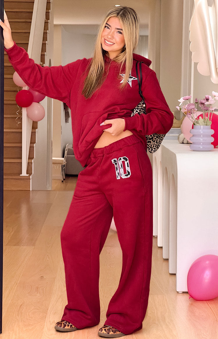 A pair of red wide-leg sweatpants with a drawstring waist featuring a number 10 applique with a black and white cow print pattern on the left thigh.