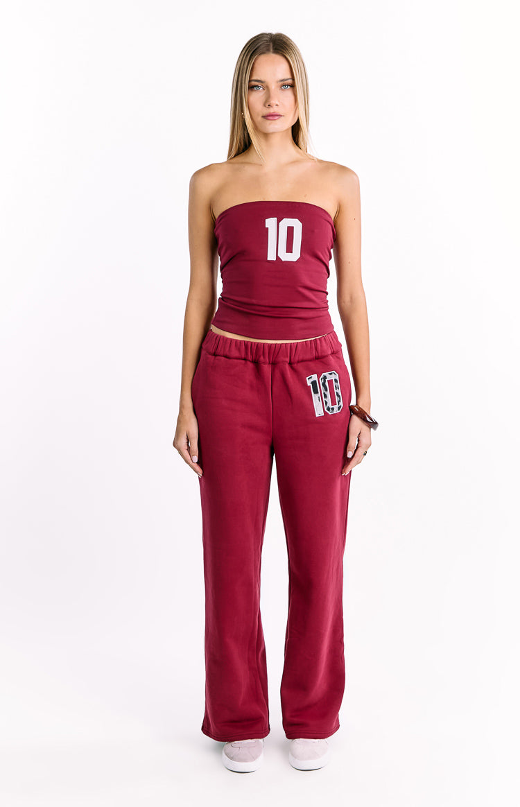 Burgundy track pants with an elasticated waistband and a leopard print 10 patch on the left thigh in a relaxed wide-leg fit
