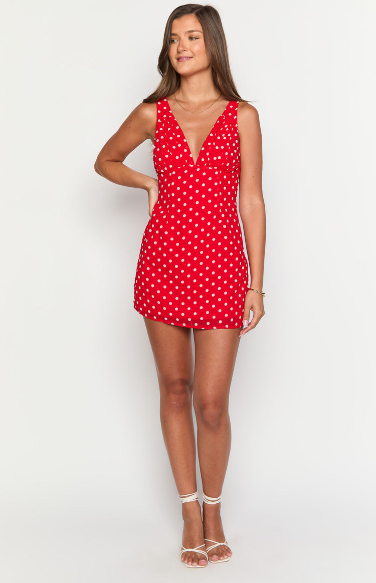 Red mini dress with white polka dots, featuring a deep V-neck, sleeveless design, and a fitted silhouette