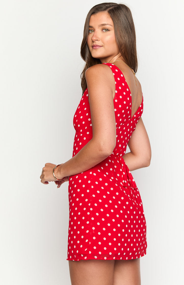 Side view of a red polka dot mini dress with a deep V-neck back and waist tie detail