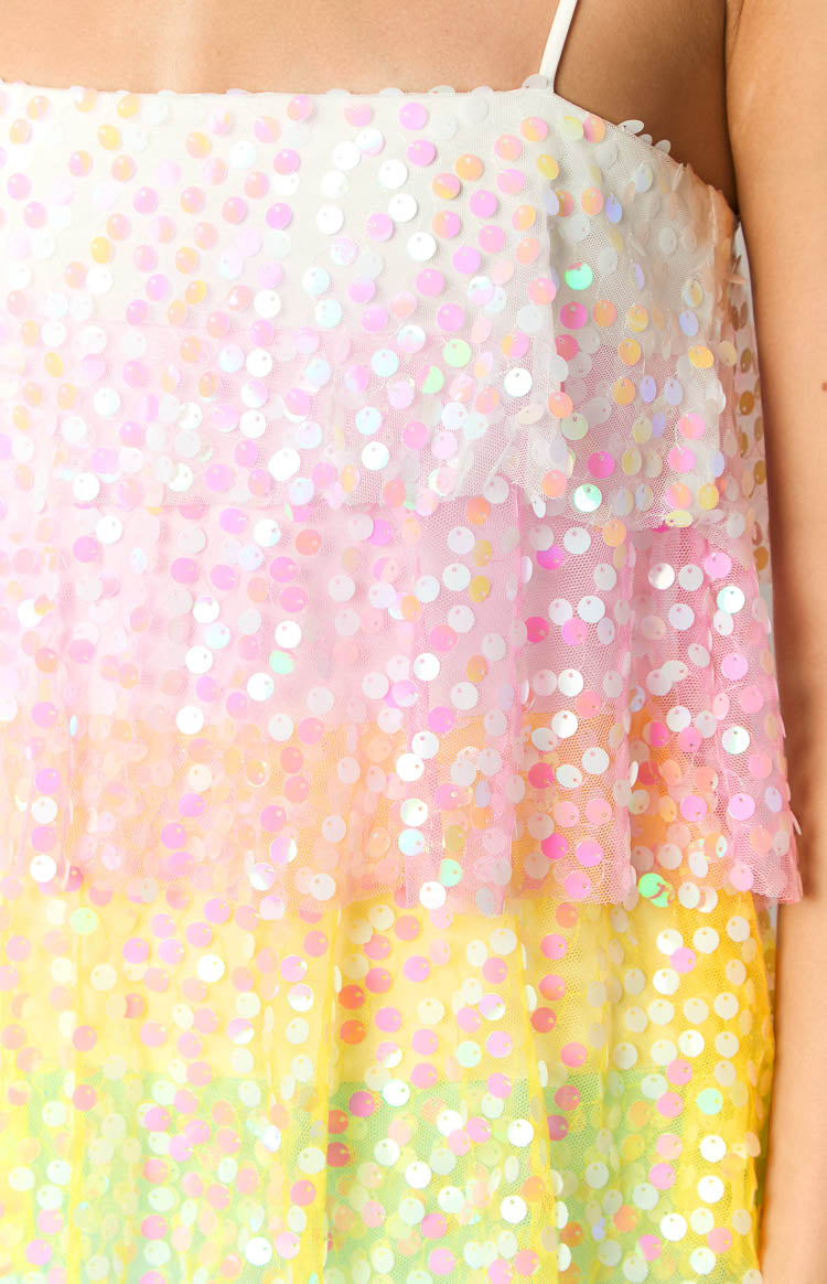 Close-up of the iridescent sequins on the layered ombre fabric of the mini dress, showing white, pink, yellow, and green