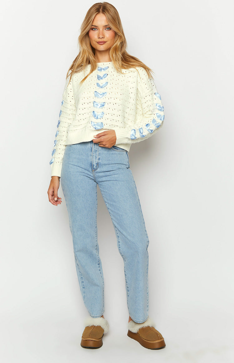 White knit cropped sweater with blue ribbon bows woven through the front and long sleeves