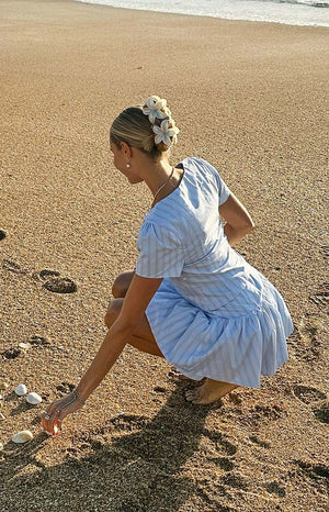 Rear view of a light blue striped top with short puff sleeves and a gathered tiered hem