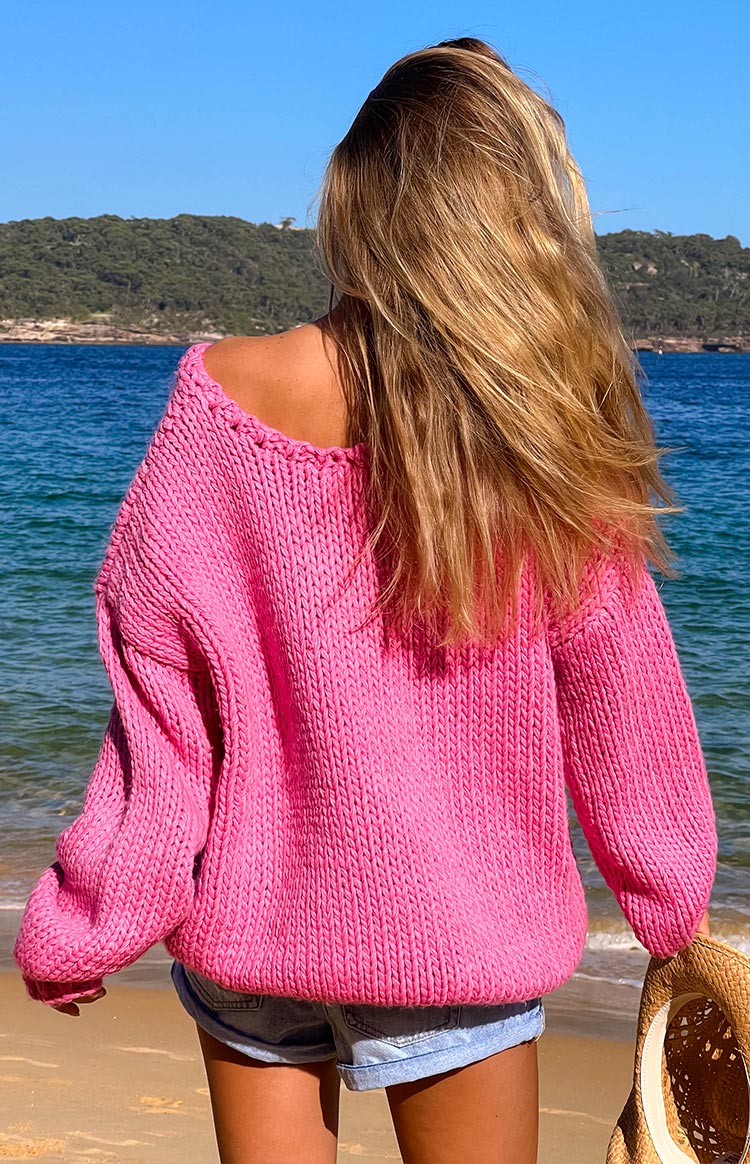Rear view of a hot pink chunky knit sweater with a wide, off-shoulder neckline