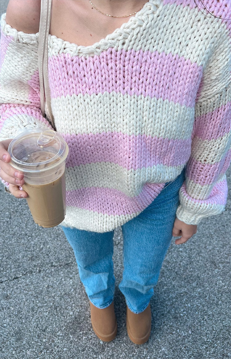 Close-up of the pink and white striped chunky knit sweater with an off-shoulder neckline and ribbed cuffs