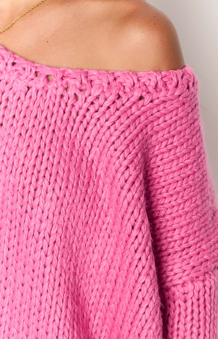 Detail shot of the hot pink chunky knit sweater's off-shoulder neckline and textured stitch pattern
