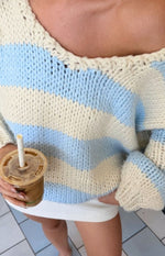 Detail shot of the V-neckline and chunky knit texture of a light blue and cream striped sweater