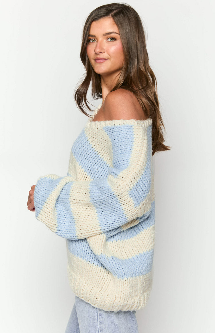 Side view of a light blue and cream striped chunky knit sweater with an off-shoulder neckline and wide sleeves